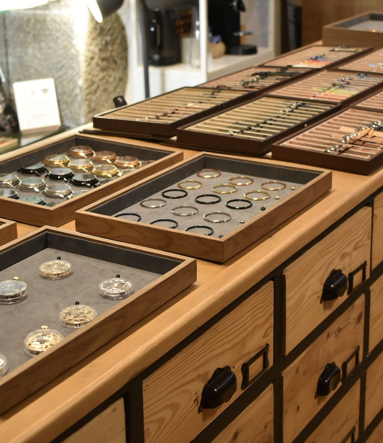 Établi de l'atelier Initium à Genève : plateaux de boîtiers, cadrans, lunettes et bracelets pour la création d'une montre sur mesure