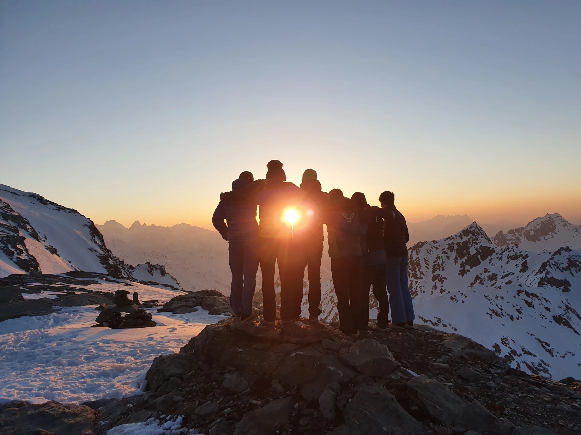 Cordée réunie au sommet face au coucher de soleil sur les Alpes