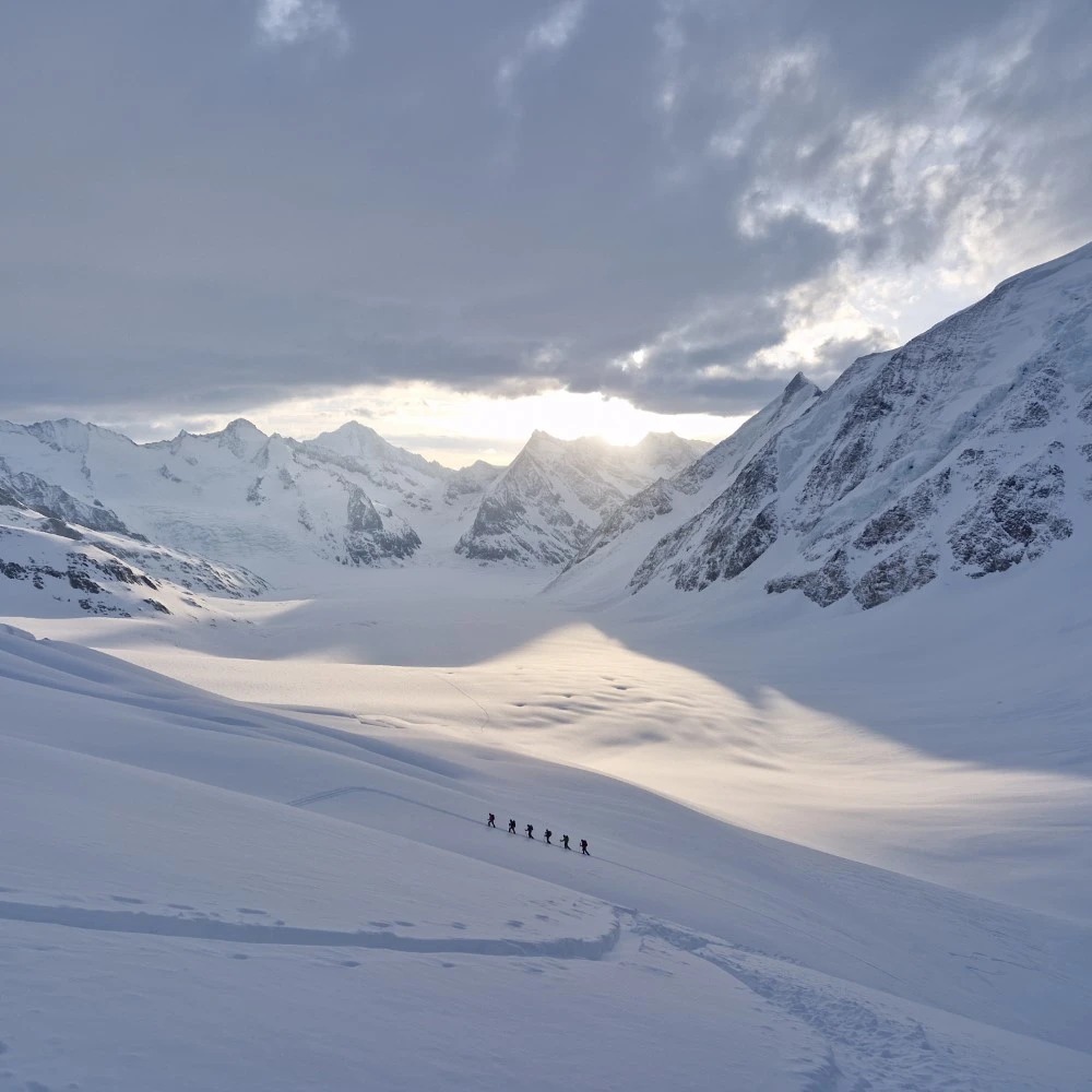 Cordée traversant un glacier des Alpes suisses au lever du jour